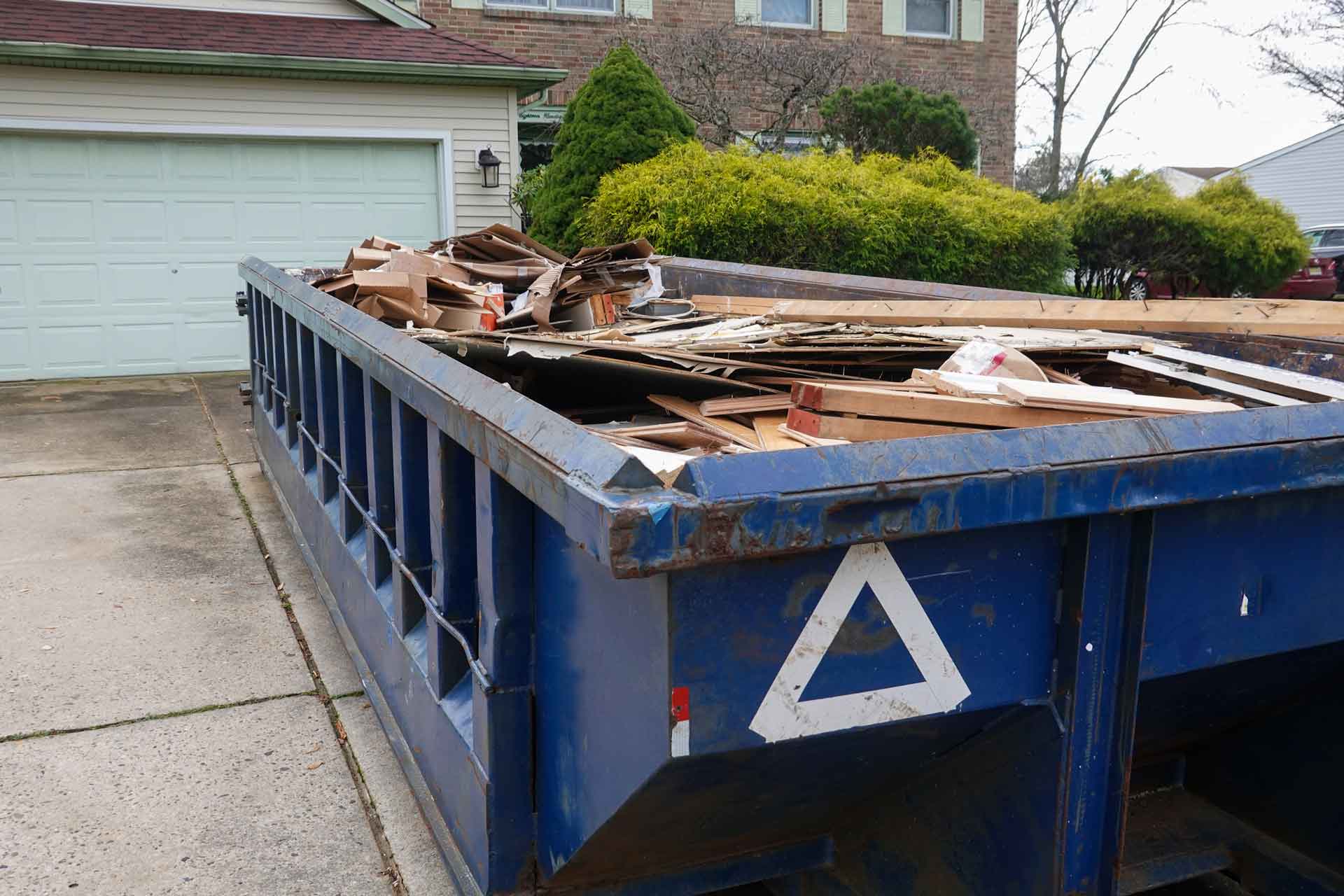 Blue rental dumpster full of wood and other construction waste