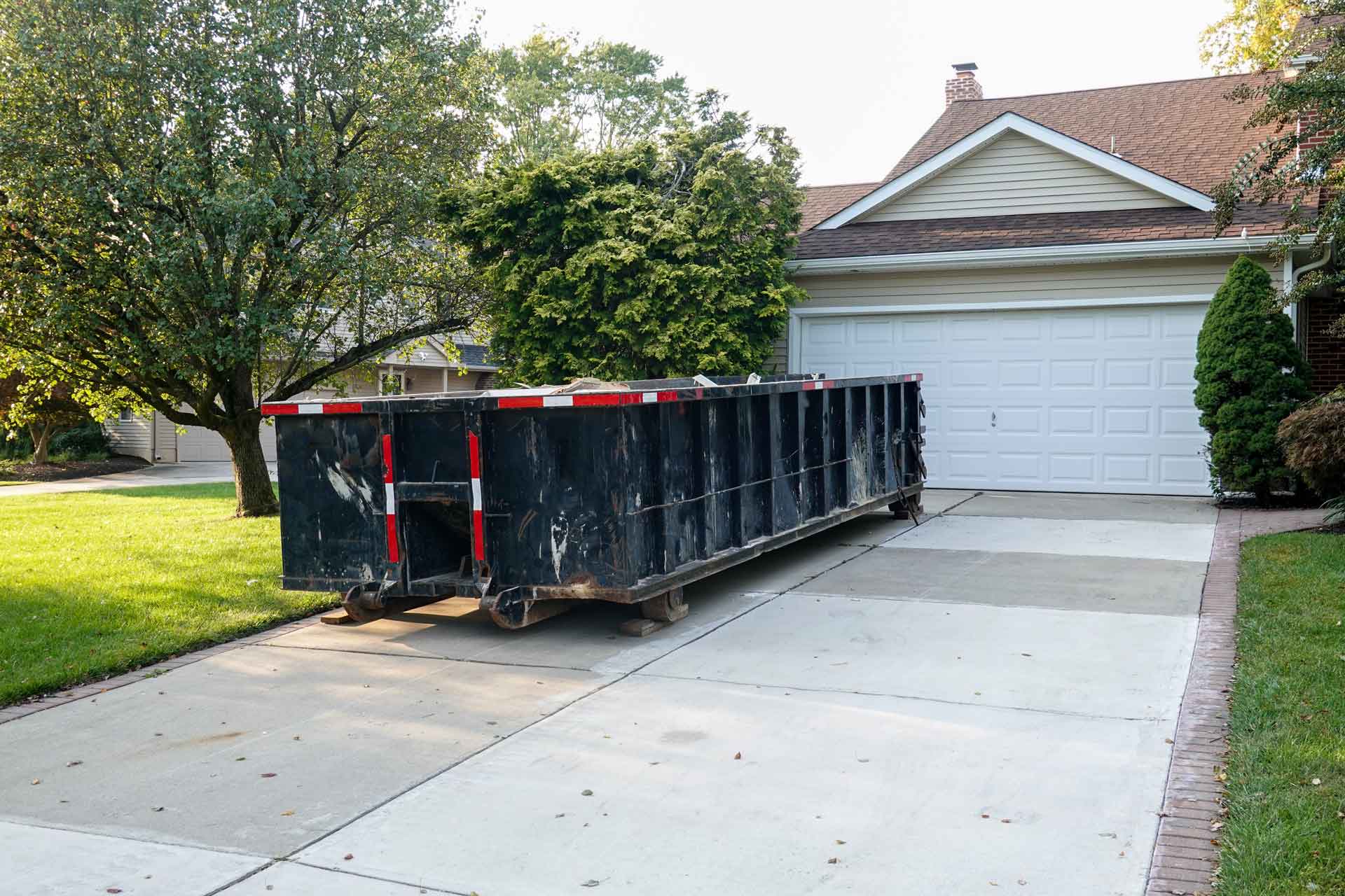 Black rental dumpster in driveway