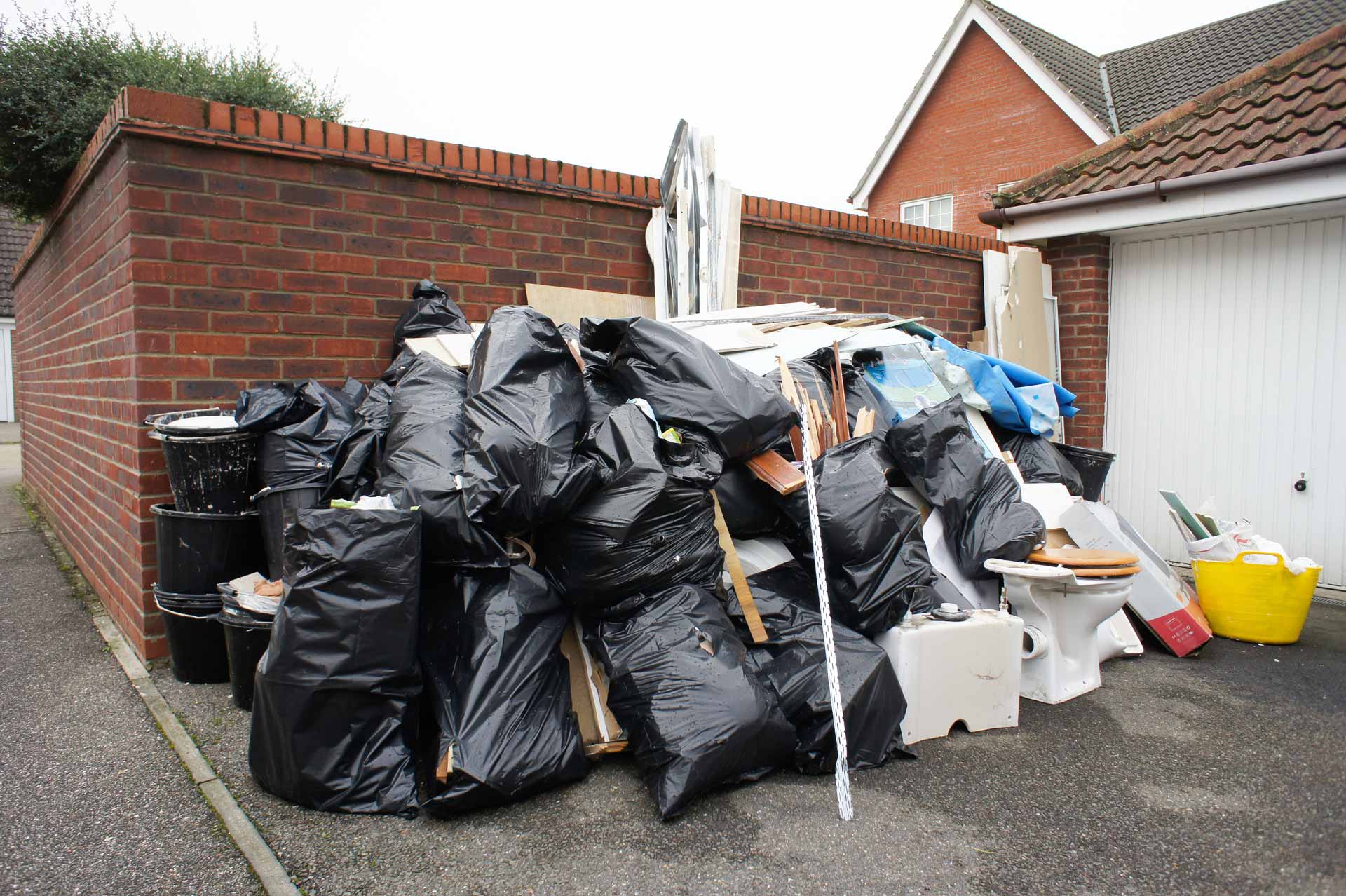 Large pile of garbage bags and household trash outside of a home